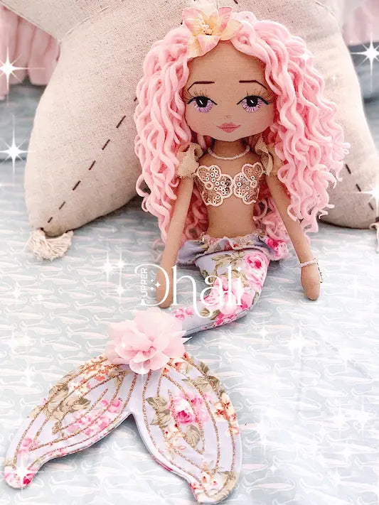 Beautiful handmade mermaid doll featuring a blue and pink floral tail, gold glitter detail, golden sequin mermaid bodice, long pink curly hair and purple hand embroidered eyes with eyelashes