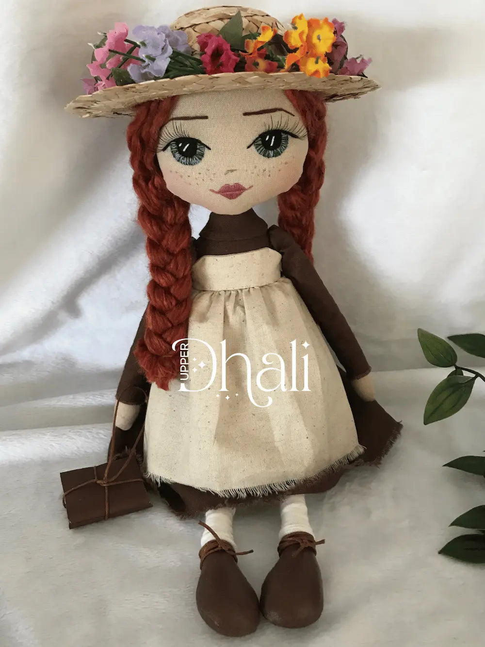 Anne Shirley Green Gables handmade doll featuring a plain brown dress, calico apron dress, long red plaits, hand embroidered face with blue eyes and a straw hat with flower detail
