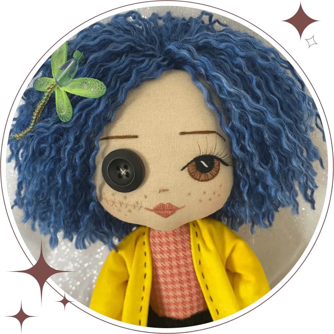 coraline handmade doll with one embroidered brown eye and one black button eye, with blue hair, green dragonfly hairclip, wearing a red and orange top and yellow jacket