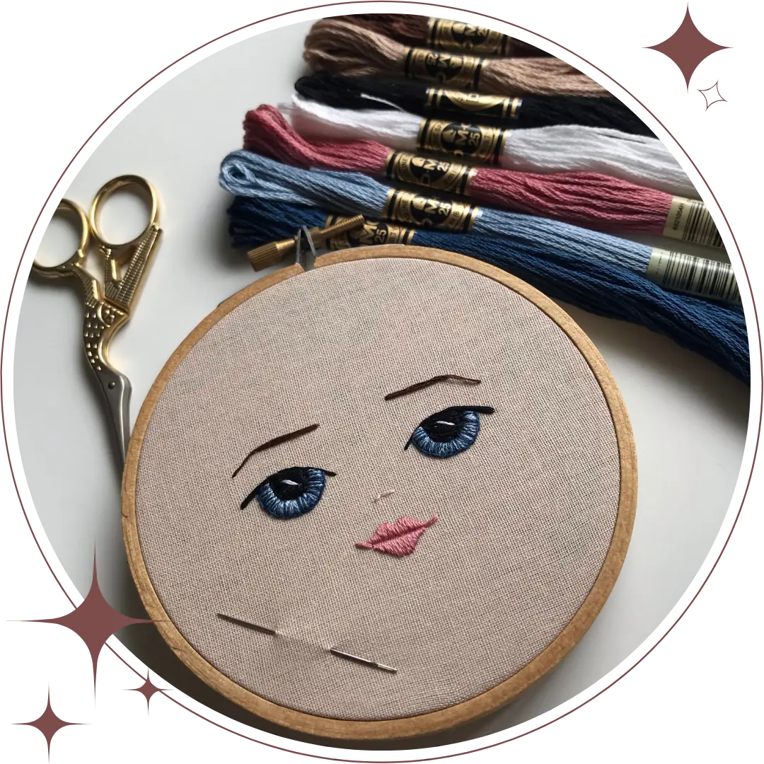 doll face hand embroidery in hoop with gold stork scissors and an assortment of dmc embroidery floss