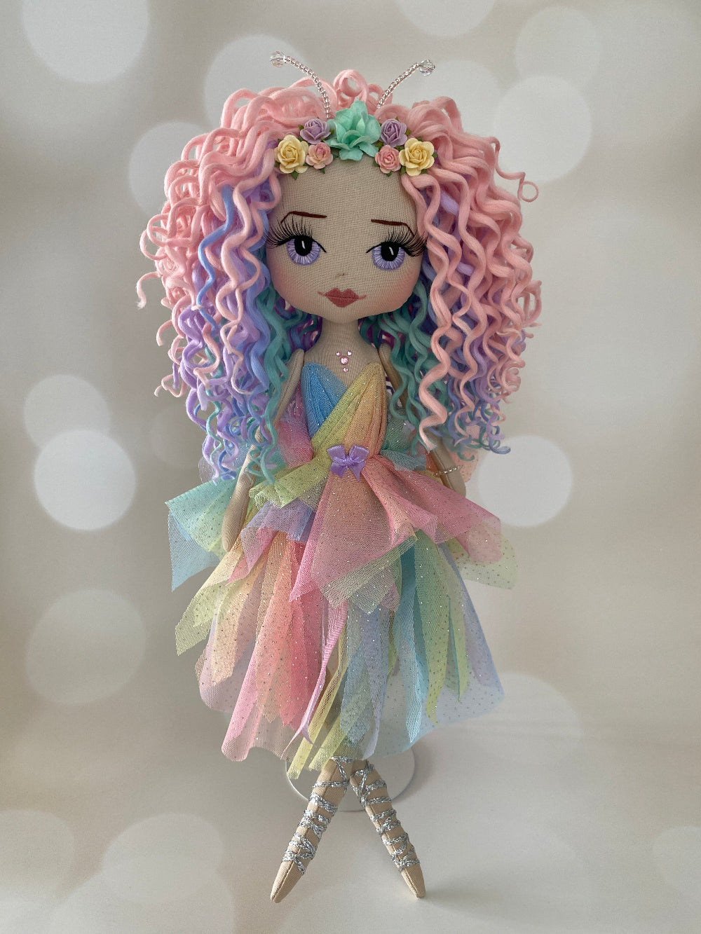 Fairy doll featuring rainbow curly hair, lavender hand embroidered eyes and a lavender sparkly dot tulle dress with silver fairy shoes
