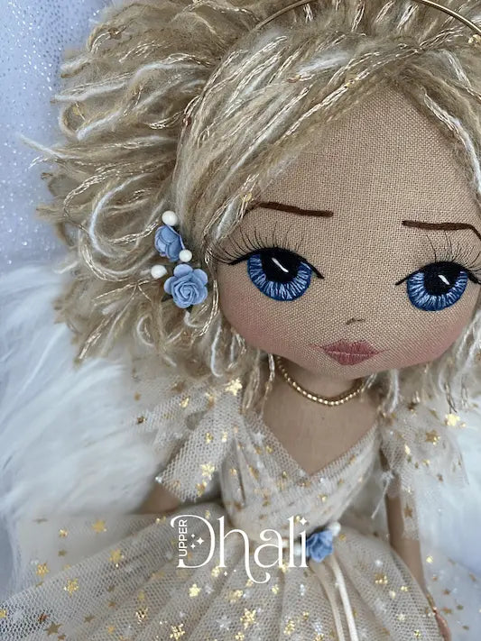 Angle Keepsake doll with hand embroidered blue eyes and blonde hair with blue roses as decoration. Wearing a gold tulle angel dress with gold stars and delicate angel wings