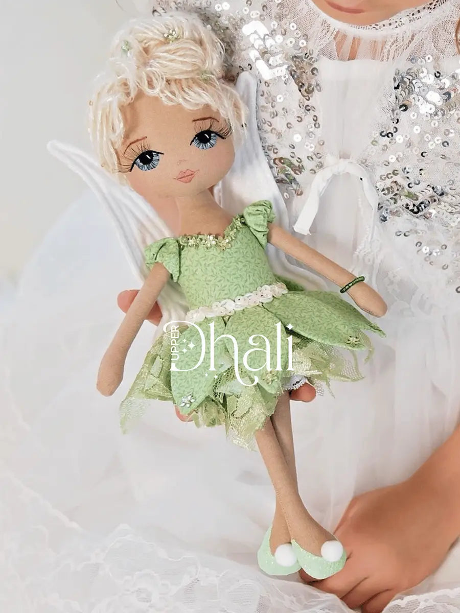 Beautiful magical fairy doll wearing a fabric leaf detail dress, green sequin detail, lace pettiskirt, white sparkle wings and blonde sequin hair