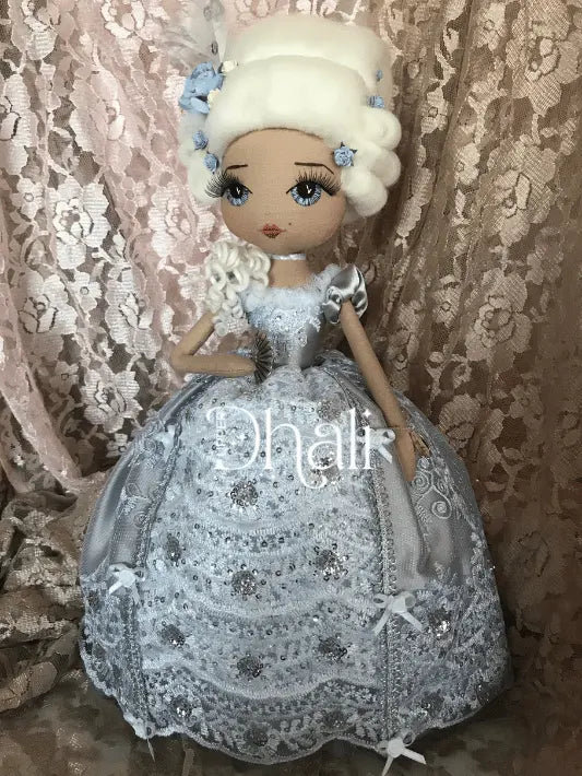 Marie Antionette handmade doll wearing a silver dress with ribbon and sequin detail, holding a silver fan and wearing blue roses in her hair