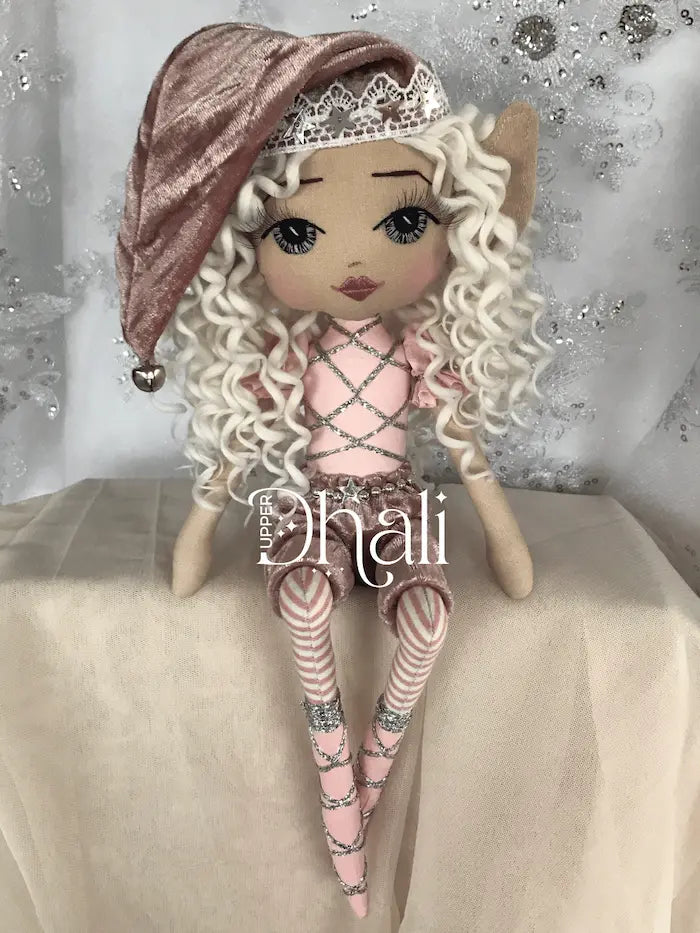 Pink and silver sitting Christmas Elf handmade doll featuring velvet shorts, white curly hair with pink velvet santa hat hand embroidered face