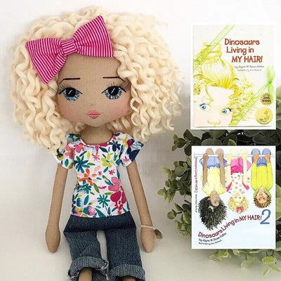 personalised handmade doll for author Jayne Rose-Vallee of Dinosaurs Living in my Hair childrens book to look like Sabrina character. Blonde short curly hair, blue hand embroidered eyes, bright pink ribbon in hair, brightly coloured tshirt and jeans
