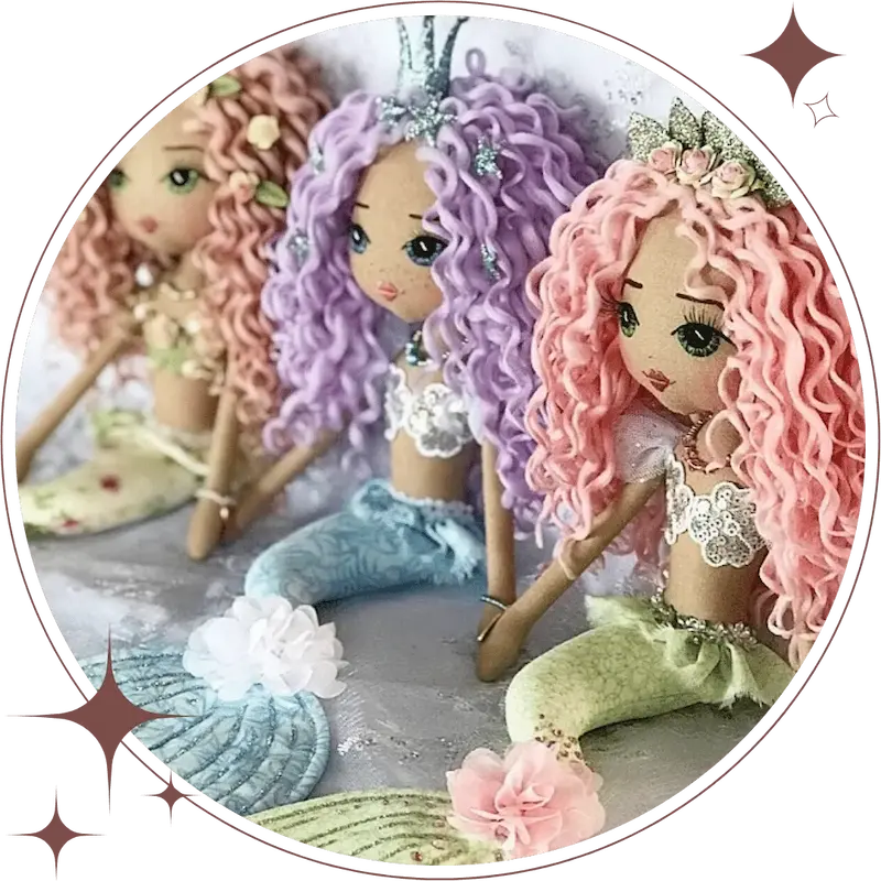 three mermaid dolls sitting in a row; rainbow colours of purple, blue, green and pink with glitter mermaid crowns