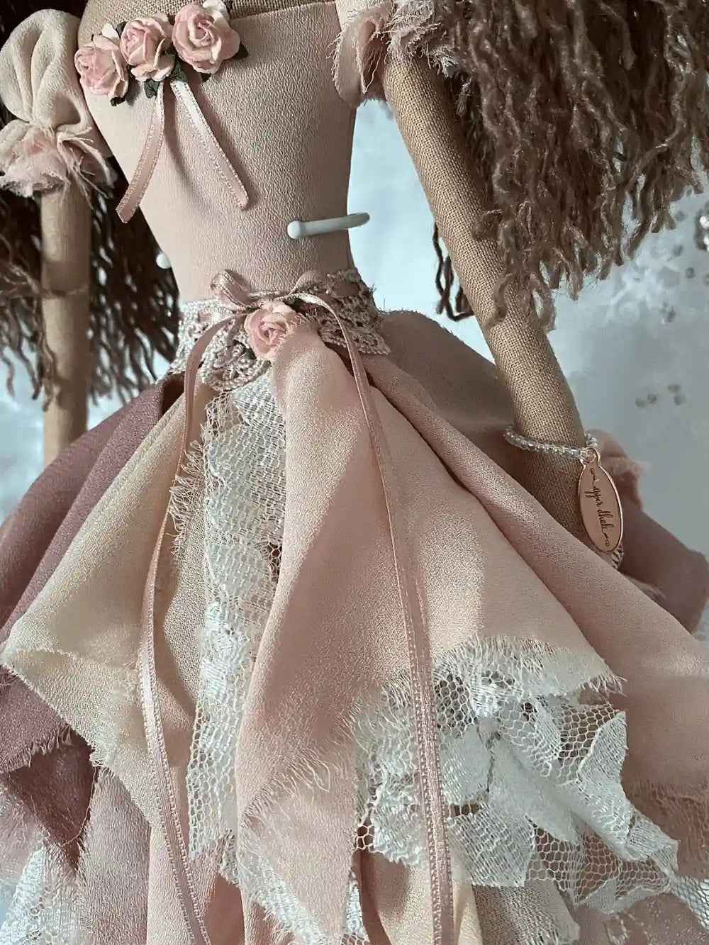 handmade doll with hand embroidered brown eyes, long brown hair in ponytails with flower detail, wearing a vintage inspired chiffon and lace dress in pink tones with flower and ribbon detail