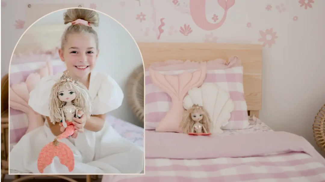 A young girl holding a mermaid keepsake doll in her mermaid themed bedroom