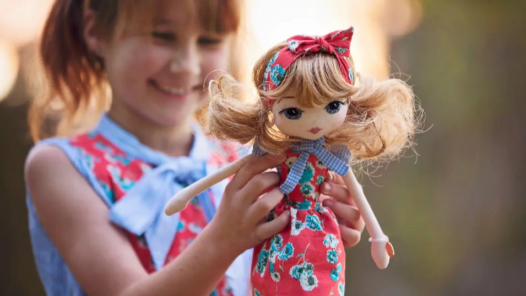A young girl holding a handmade doll wearing the same dress