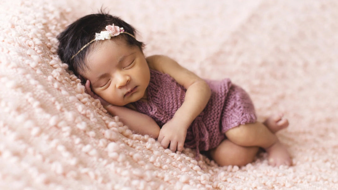 Sleeping newborn baby wrapped in lavender blanket, symbolising gentle and beautiful baby girl name inspiration
