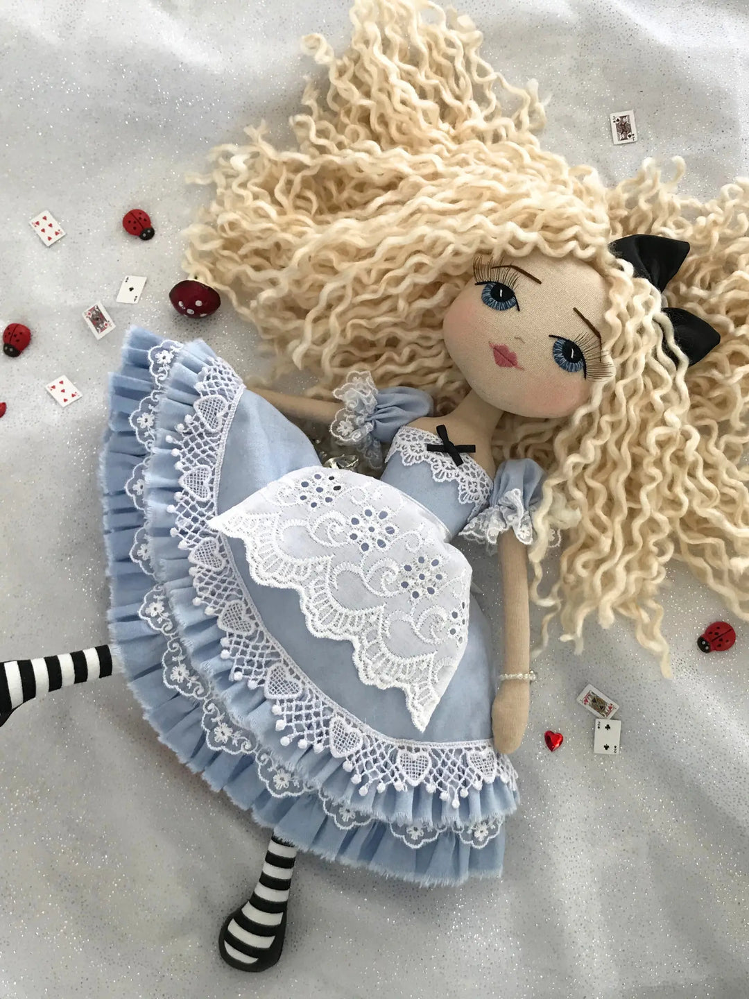Textile doll with blonde hair and a blue dress on a light gray background
