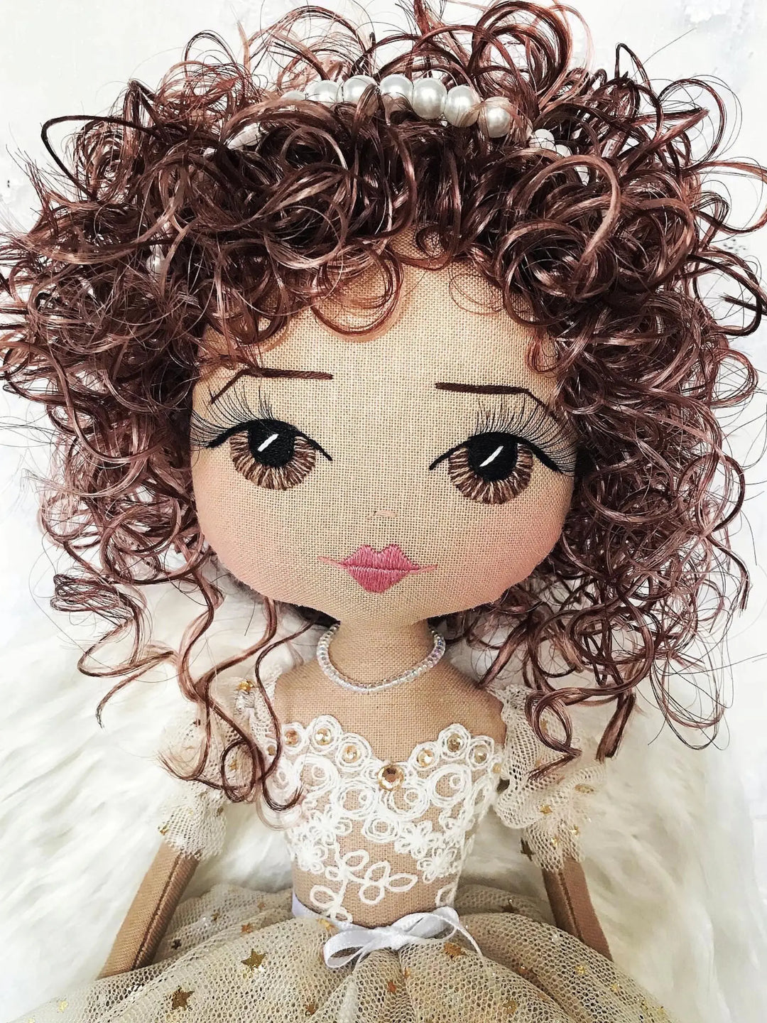 Textile doll with curly hair and a detailed outfit on a white background