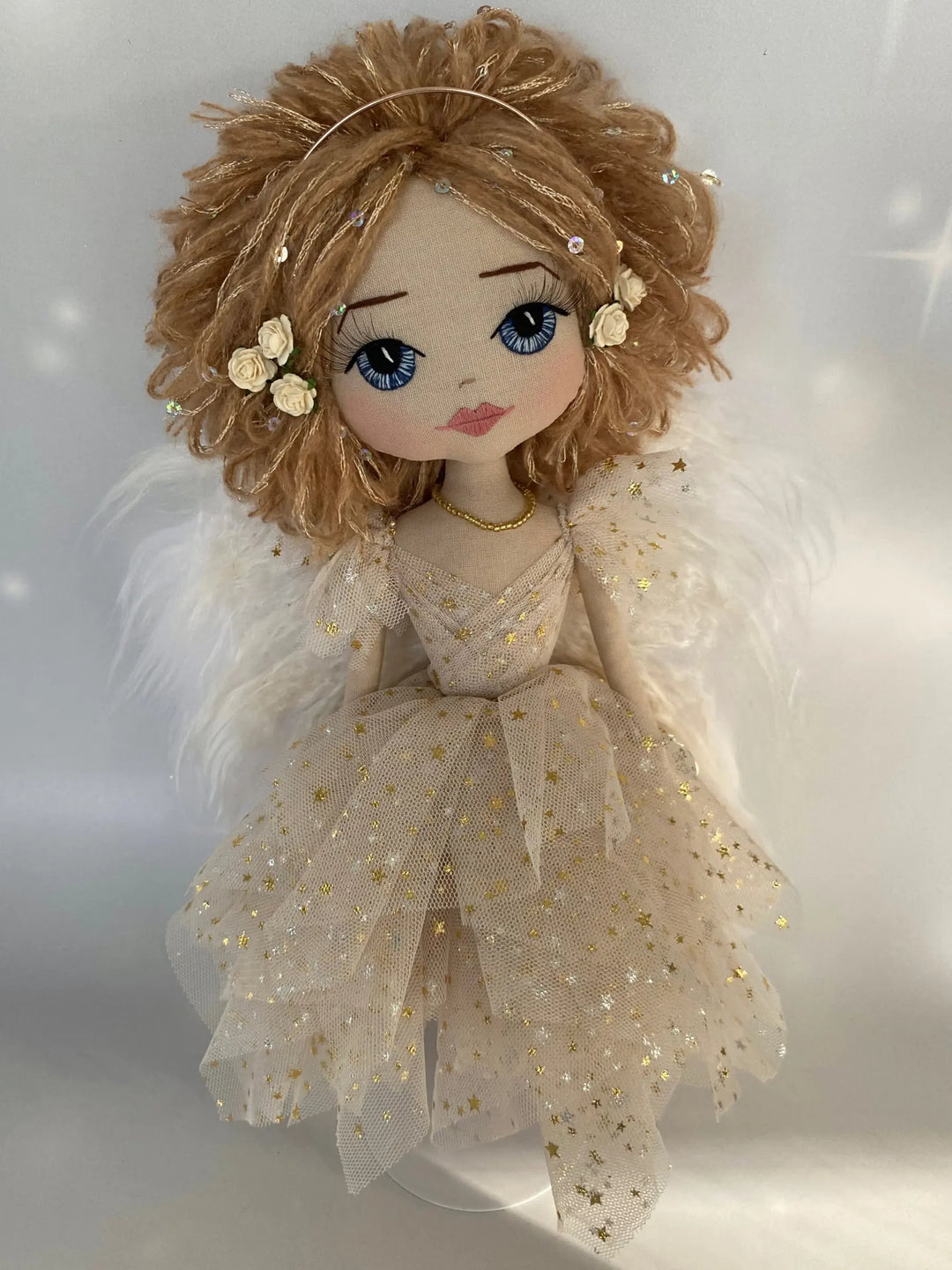 Decorative angel doll with blonde hair, blue eyes, and a gold dress on a white background