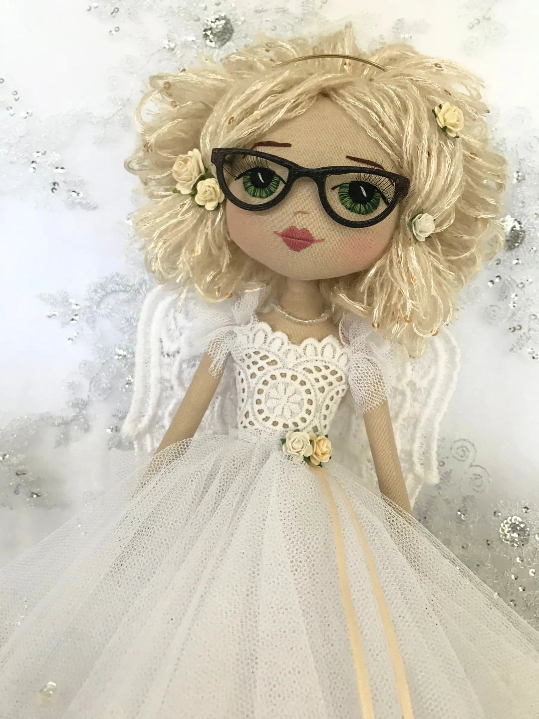 Doll with blonde hair, glasses, and a white dress on a decorative background