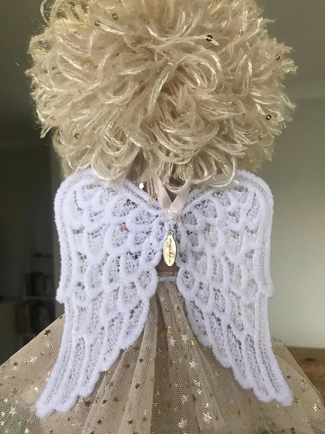Decorative angel figure with lace wings on a neutral background