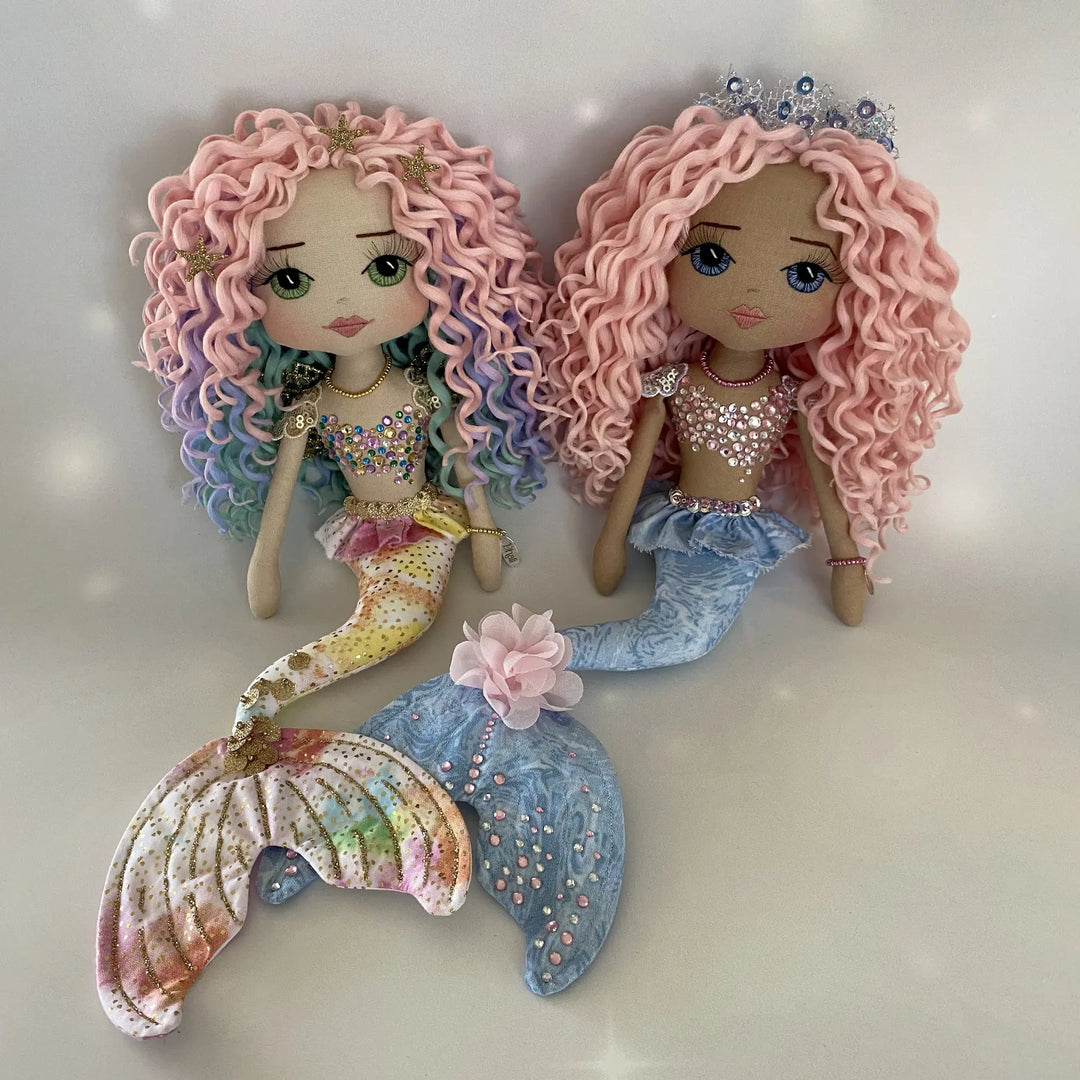 Two handmade mermaid art dolls by Upper Dhali displayed together, showcasing different skin tones, pastel curls, and jeweled details.