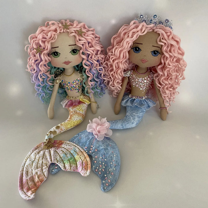 Two handmade mermaid art dolls by Upper Dhali displayed together, showcasing different skin tones, pastel curls, and jeweled details.