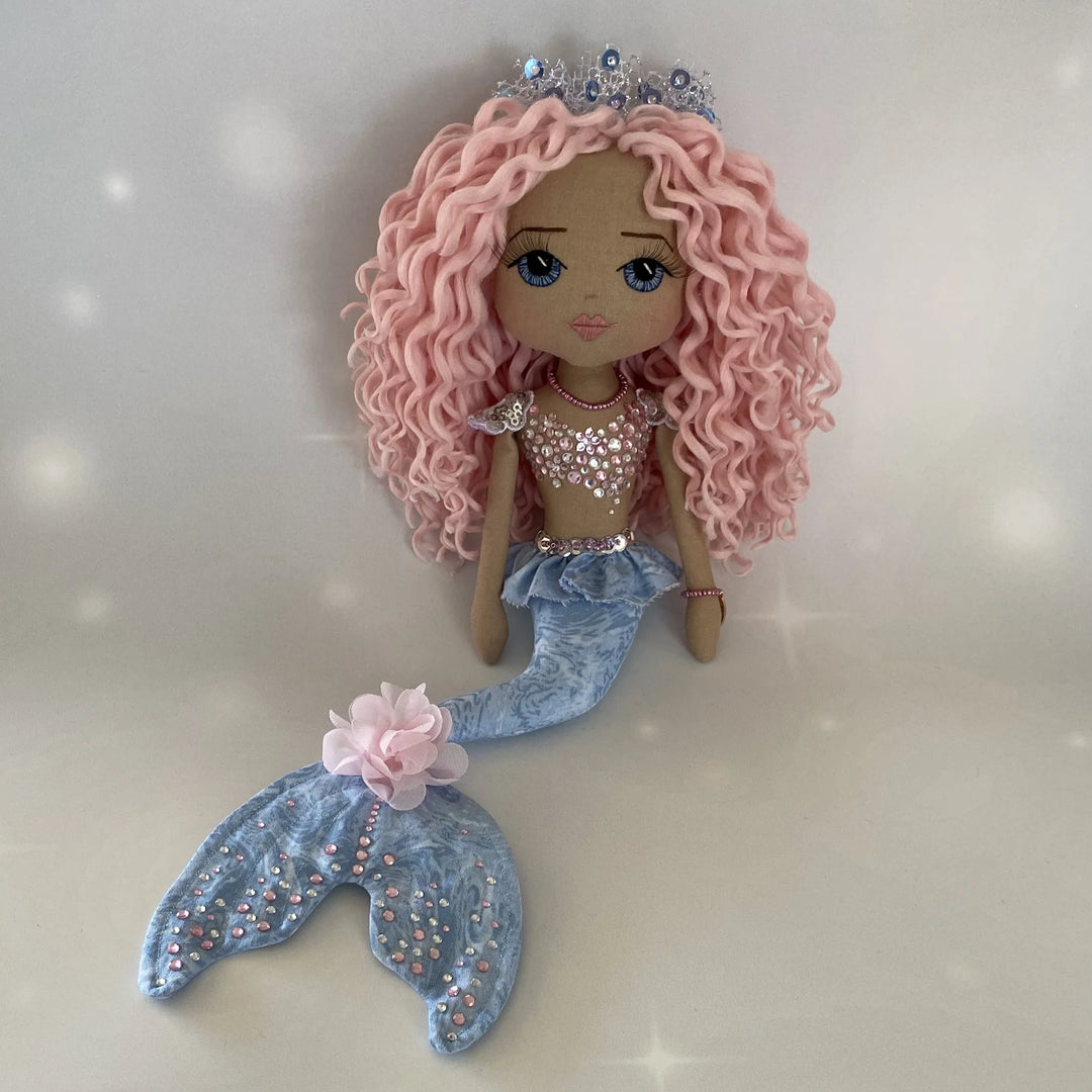 Full-length image of Mirren the mermaid art doll, featuring her blue and blush-pink tail and pastel curls.