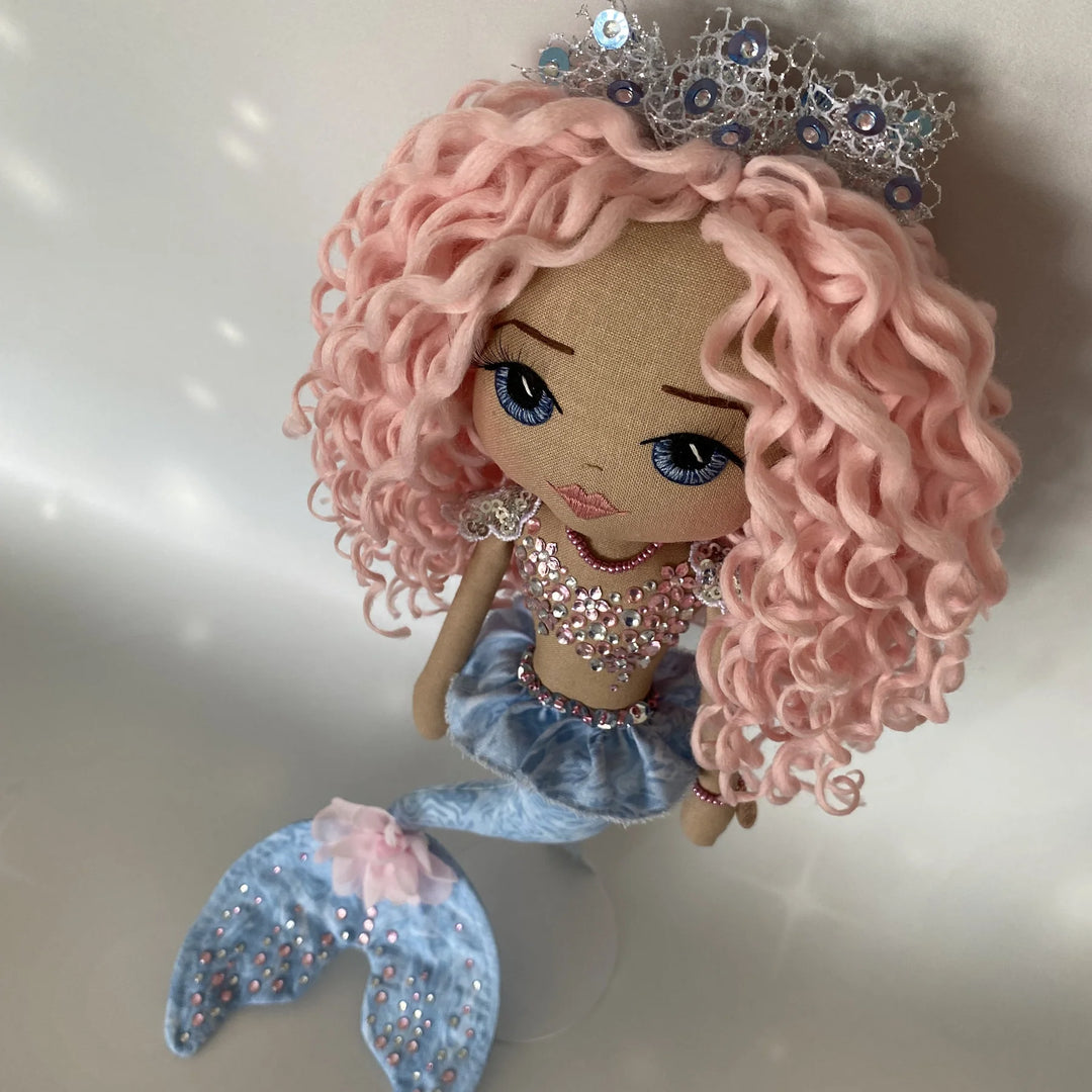 Top-view of Mirren the mermaid doll, highlighting her curls, tiara, and the upper details of her design.
