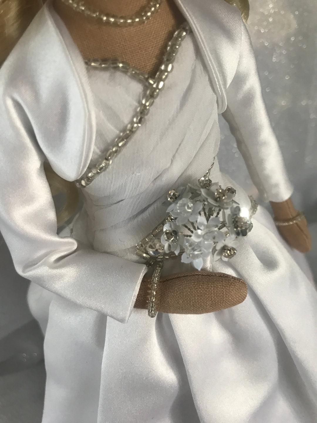 Wedding dress keepsake doll close up detail of bodice beading, bolero jacket and silver and white flower bouquet