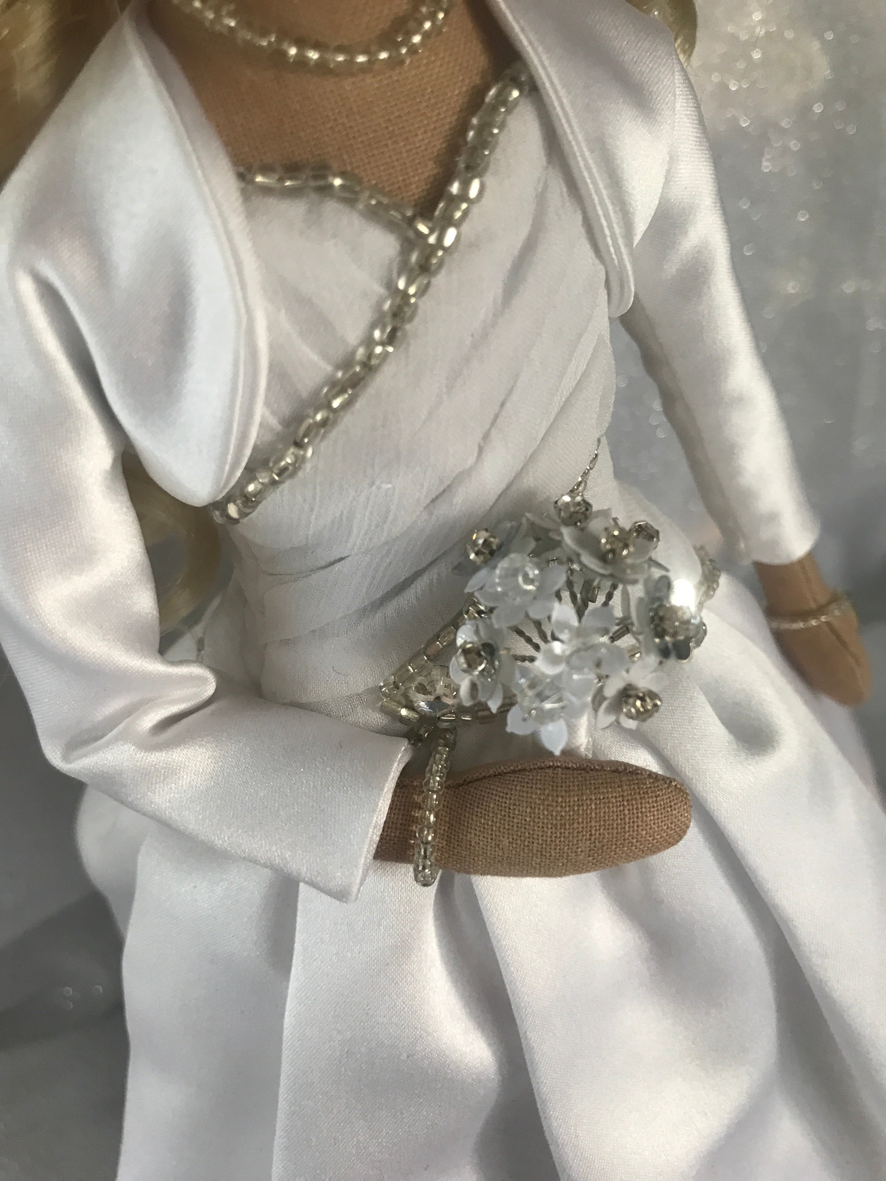 Wedding dress keepsake doll close up detail of bodice beading, bolero jacket and silver and white flower bouquet