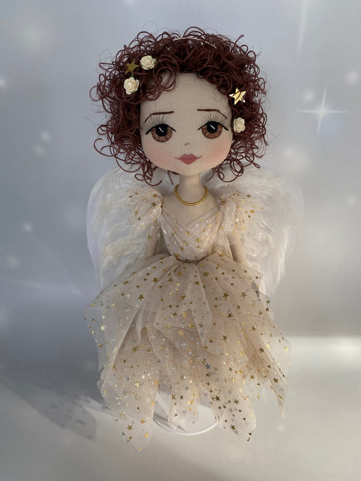 Angel keepsake doll featuring hand embroidered face with brown eyes, short curly brunette hair, gold star angel gown and eri silk and mohair angel wings
