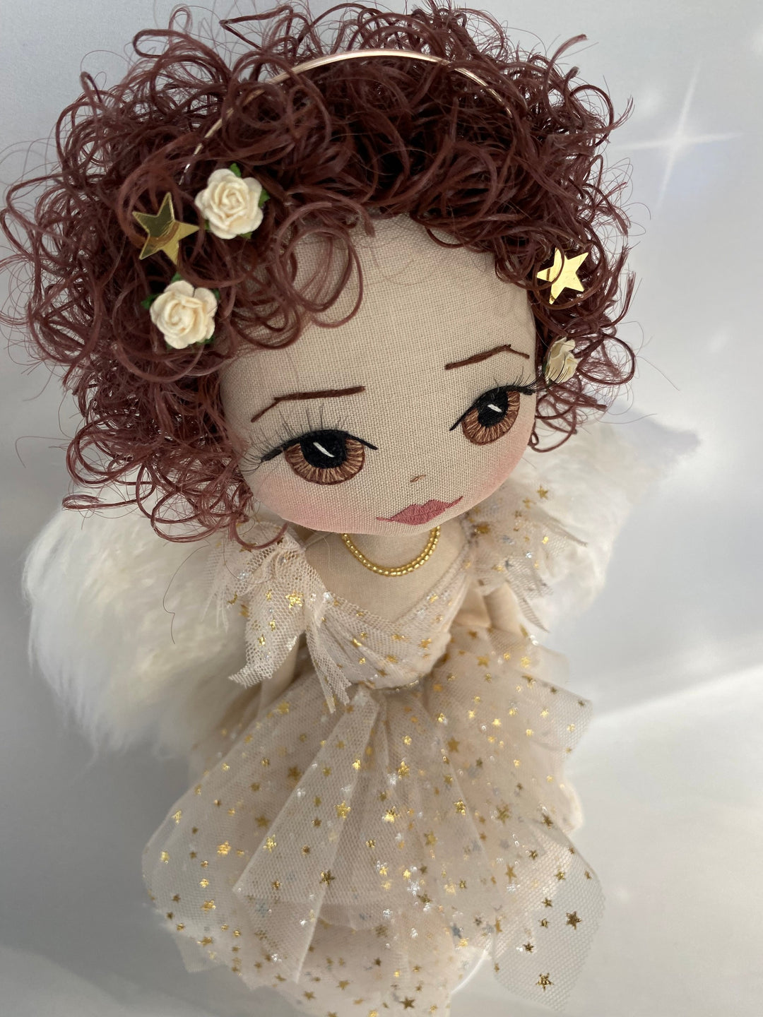 Golden angel keepsake doll with brown curly hair and gold star tulle angel gown showing curly brown hair and cream rose detail in her hair