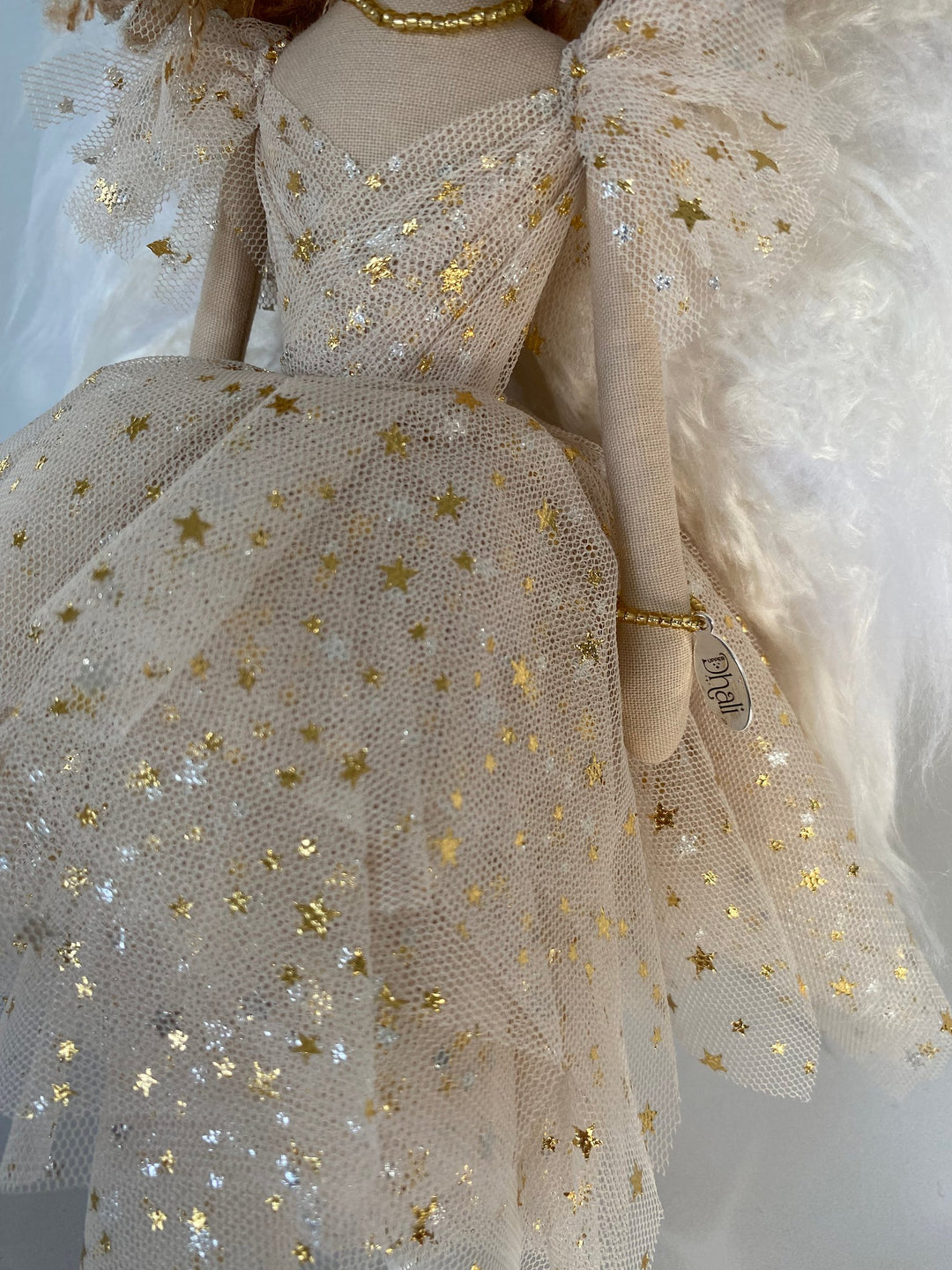 Golden angel doll close up view of angel gown featuring small gold stars