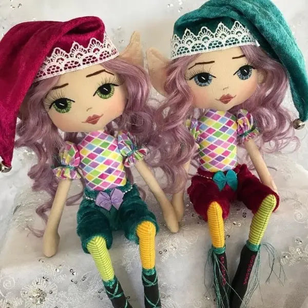Two colorful elf dolls with purple hair and checkered outfits on a light background.