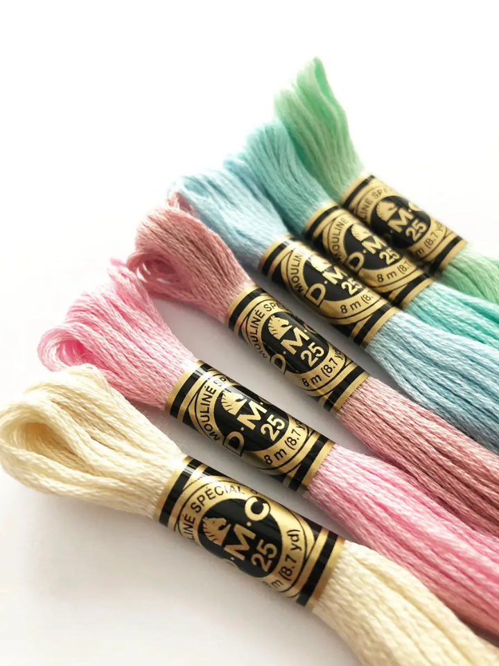 Four spools of embroidery thread in pastel colors 