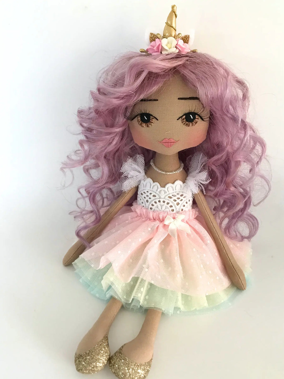 Doll with pink hair and a unicorn horn, wearing a pink dress with white lace top made by Upper Dhali.