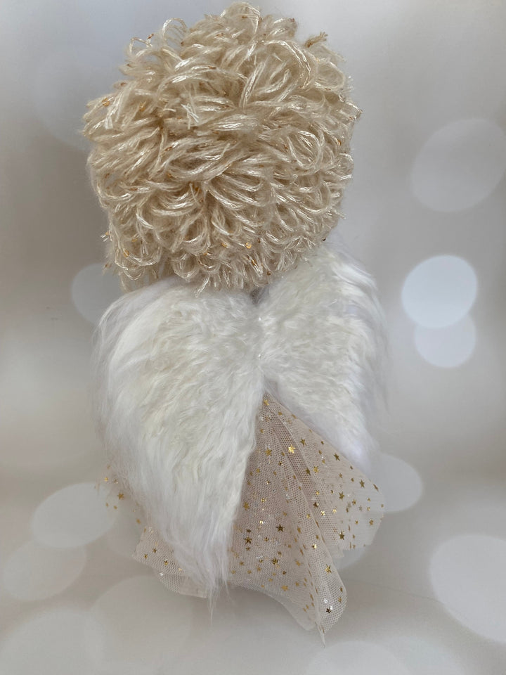 Decorative angel figure with a textured body and white wings on a blurred background