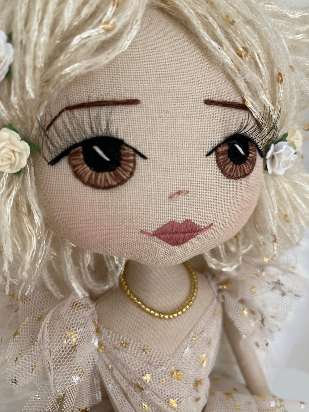 Close-up of a decorative doll with detailed facial features and floral hair accessories.