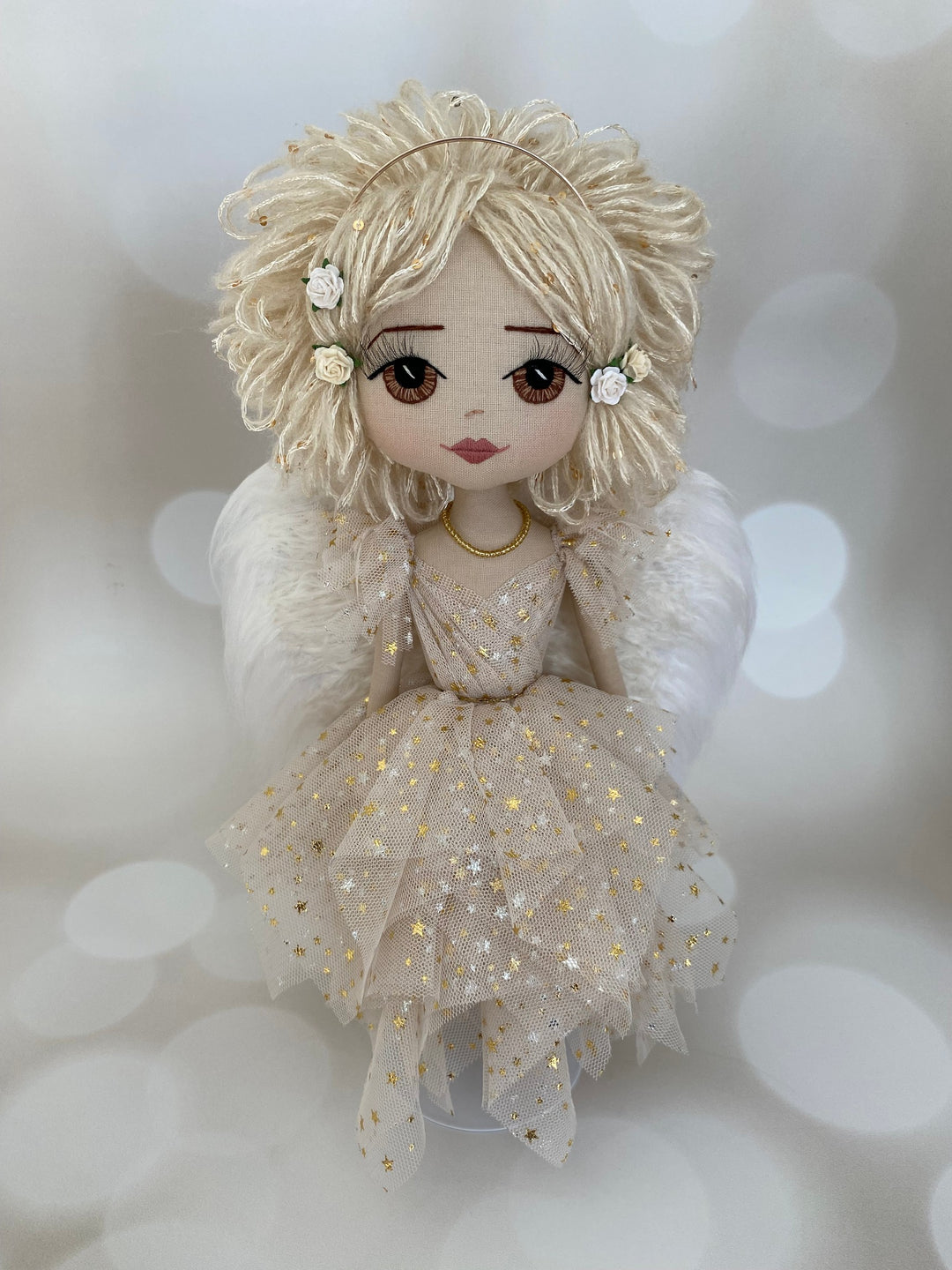 Decorative angel doll with blonde hair and a gold dress on a soft white background