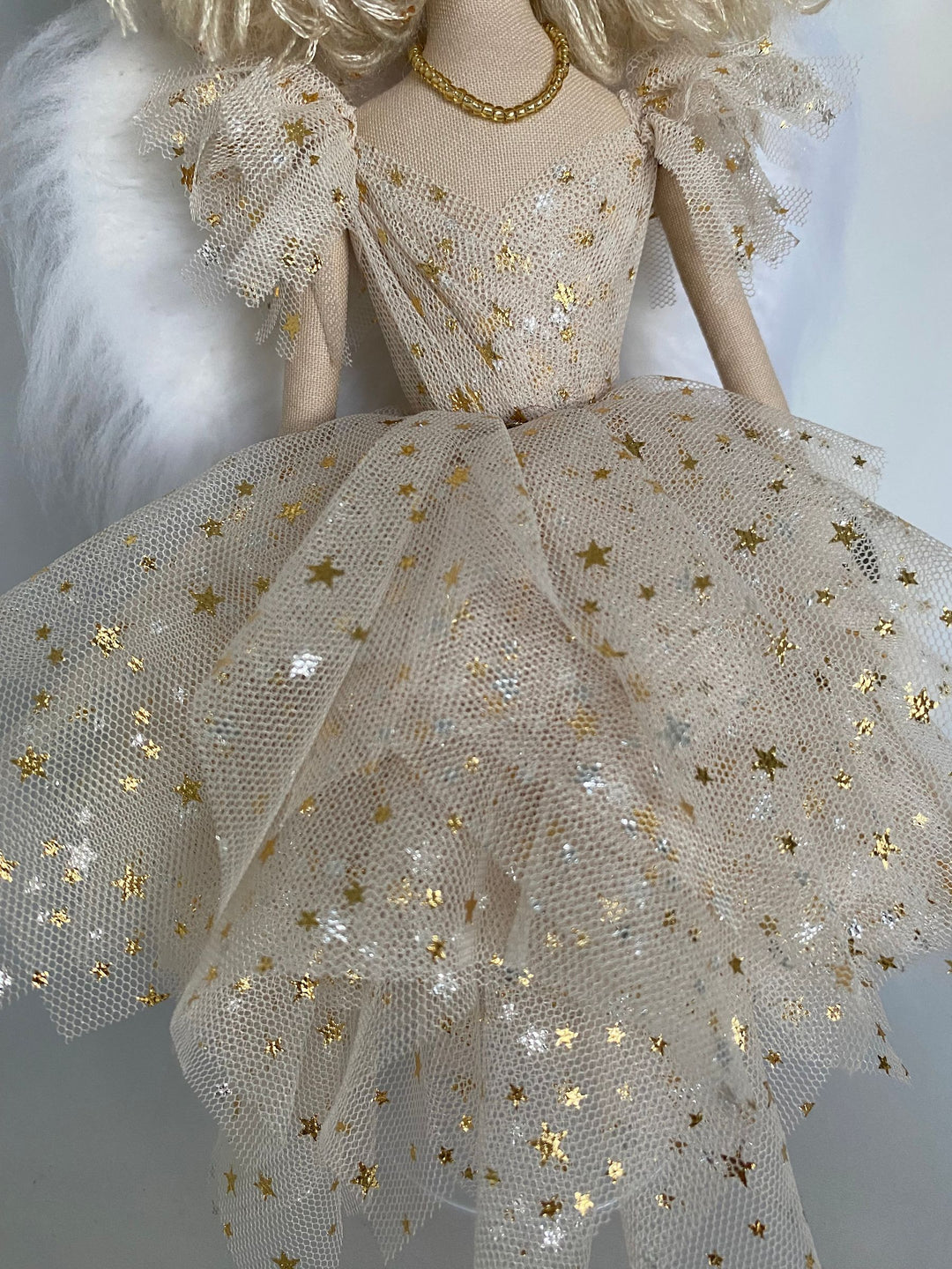 Doll wearing a detailed dress with gold star patterns on a plain background