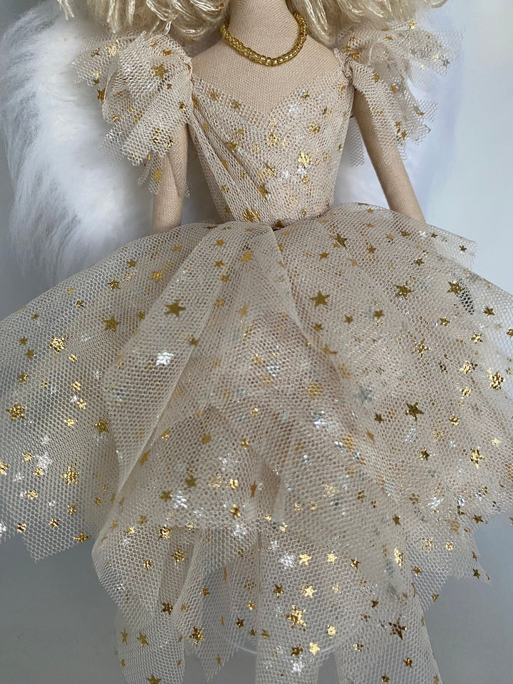 Doll wearing a detailed dress with gold star patterns on a plain background