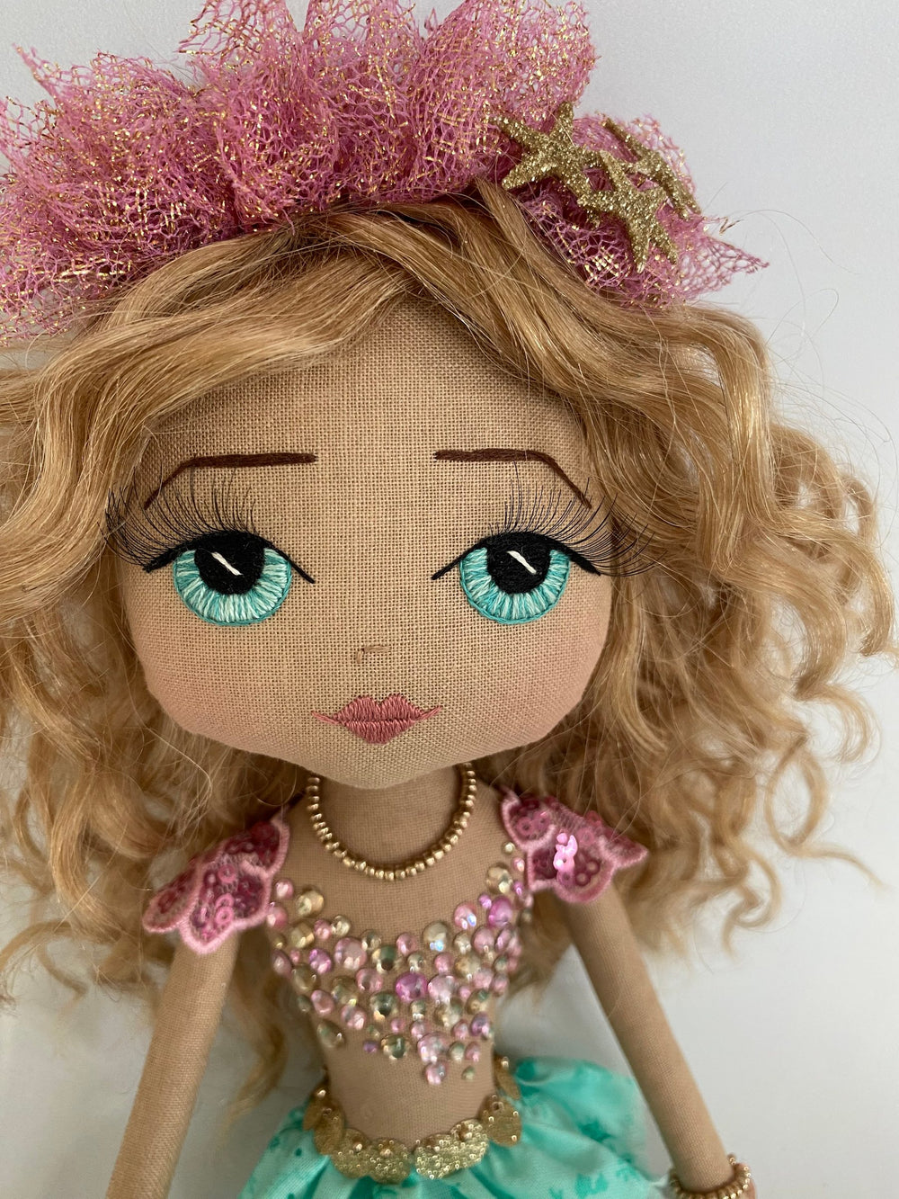 Doll with blonde hair, blue eyes, and decorative clothing on a white background
