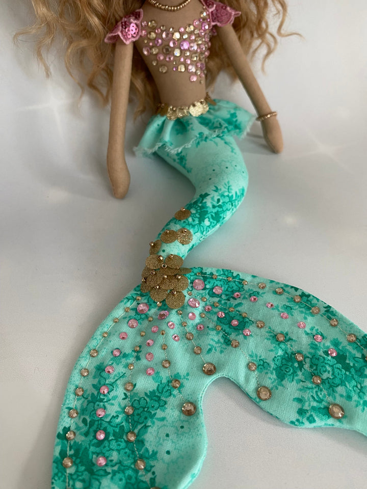Mermaid doll with a green tail and pink top on a white background