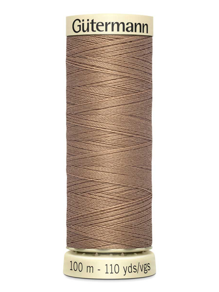 Spool of beige Gutermann thread on a white background