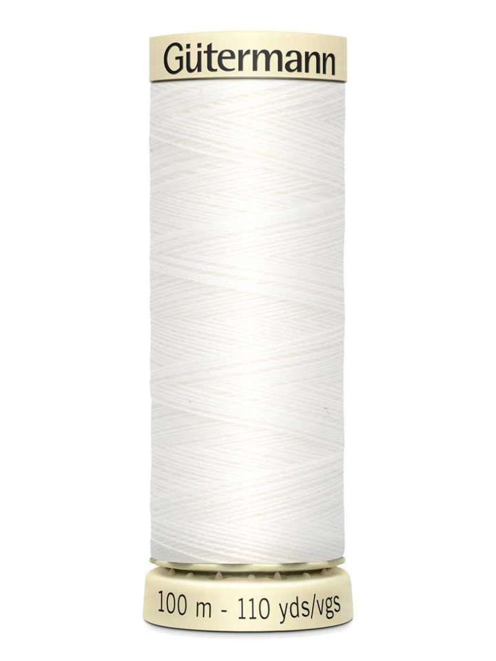 Spool of white Gutermann thread on a white background