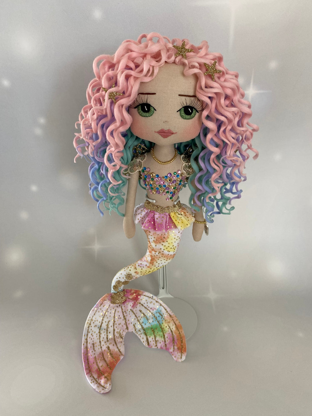 Mermaid doll with pastel-colored hair and tail on a light gray background