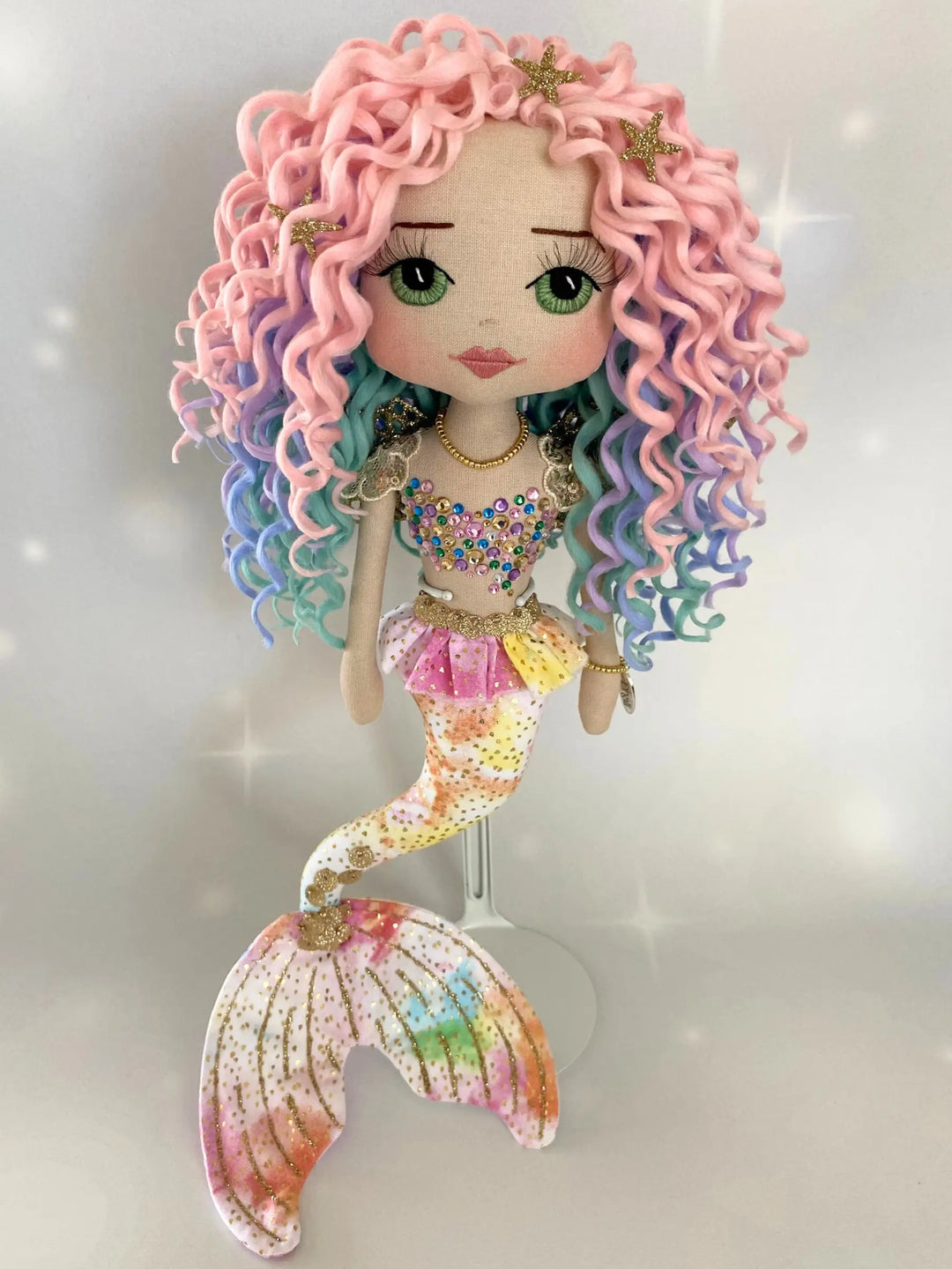 Mermaid doll with colorful hair and tail on a light gray background