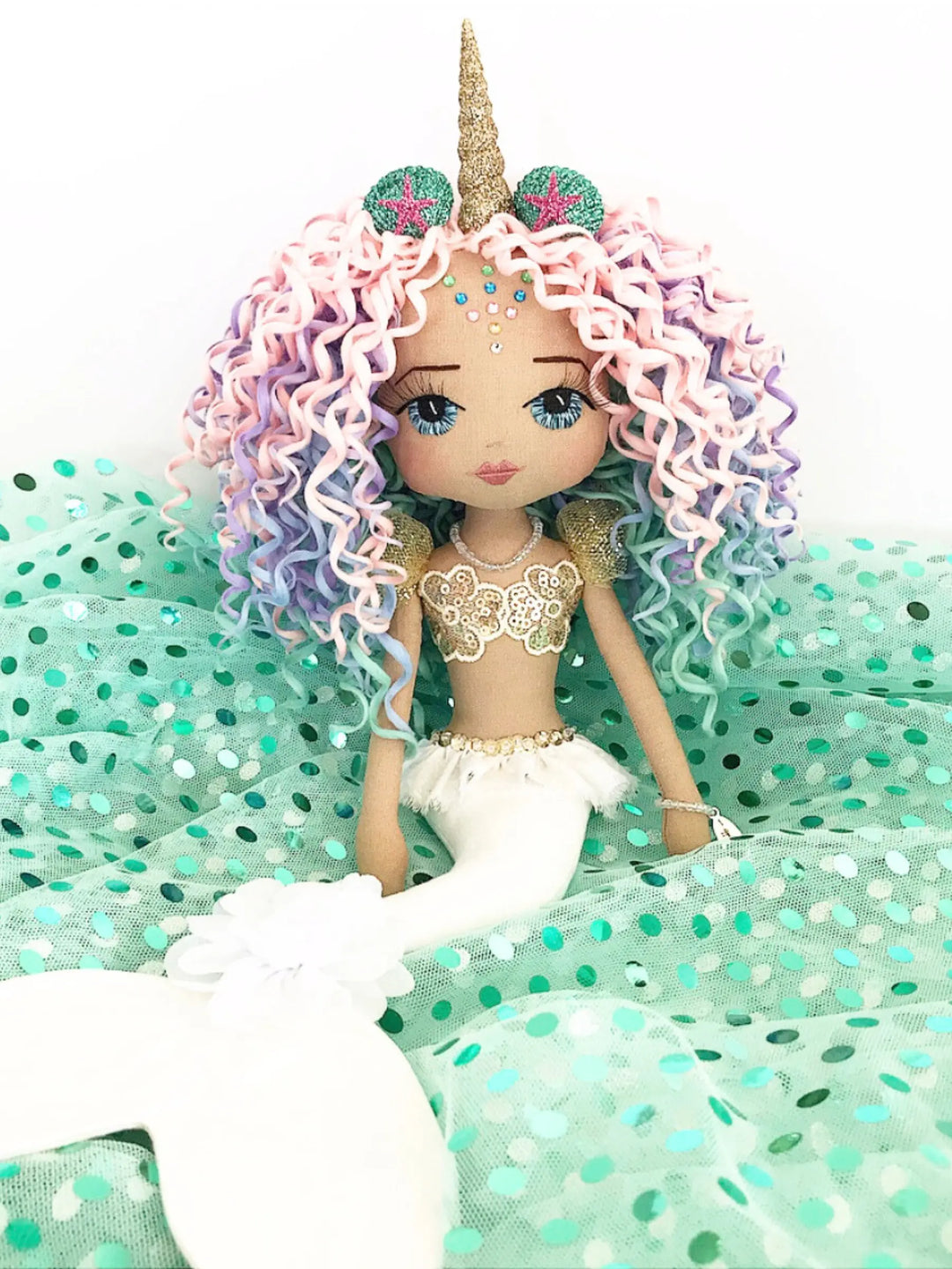 Mermaid doll with unicorn horn and colorful hair on a green polka dot background