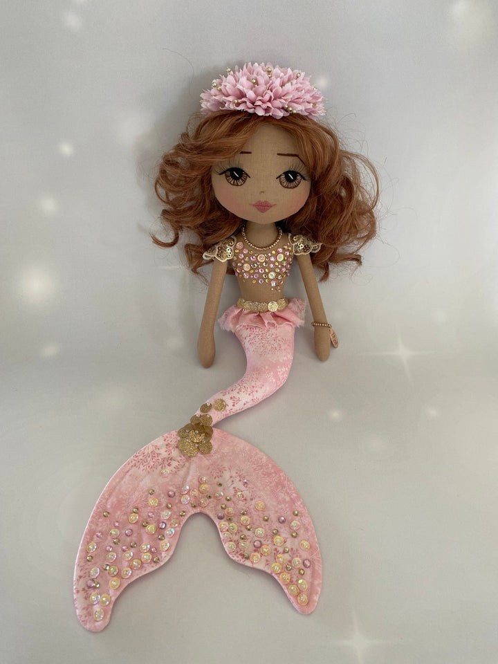 Mermaid doll with pink tail and headpiece on a white background