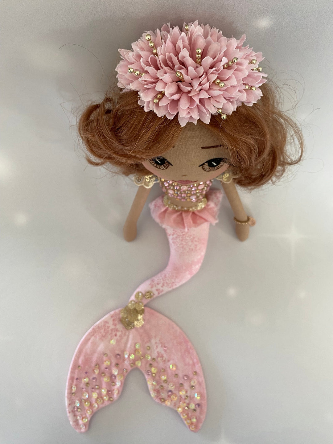Mermaid doll with pink hair and tail on a light gray background