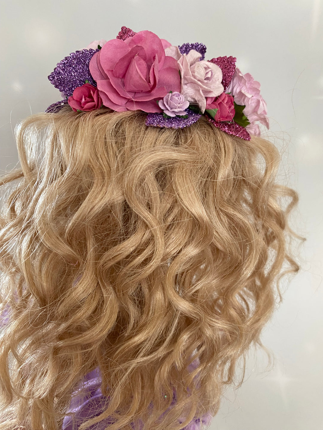 Blonde hair with pink and purple floral accessory on a white background