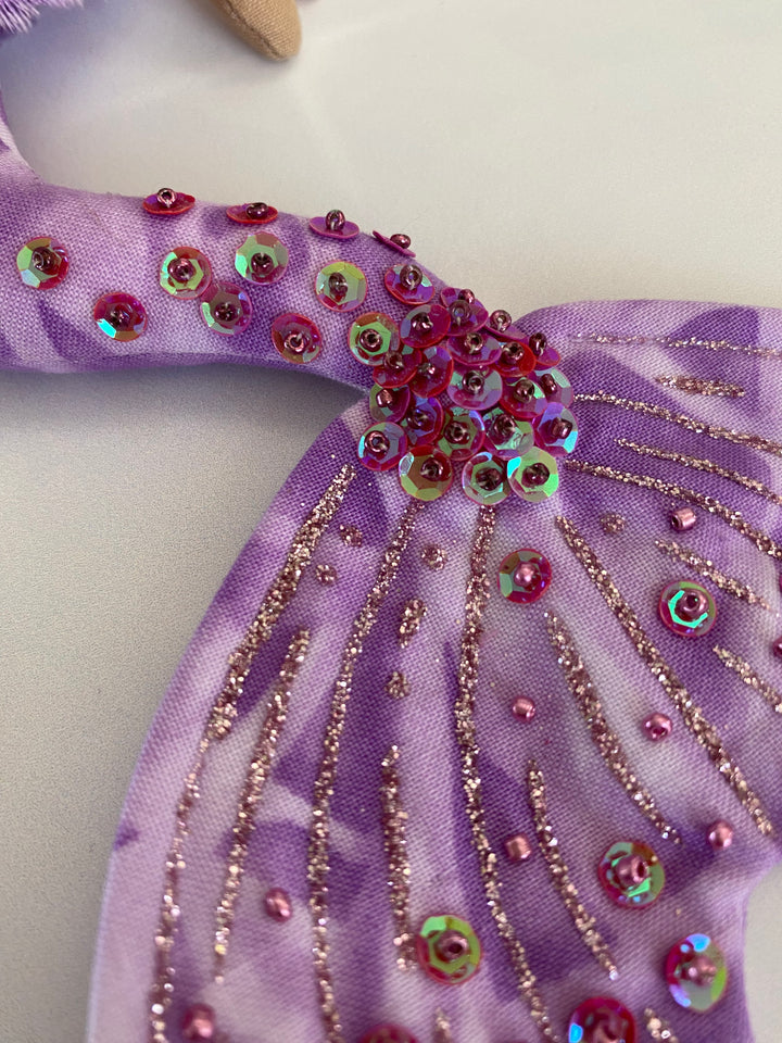 Purple fabric with decorative beads and sequins on a light background
