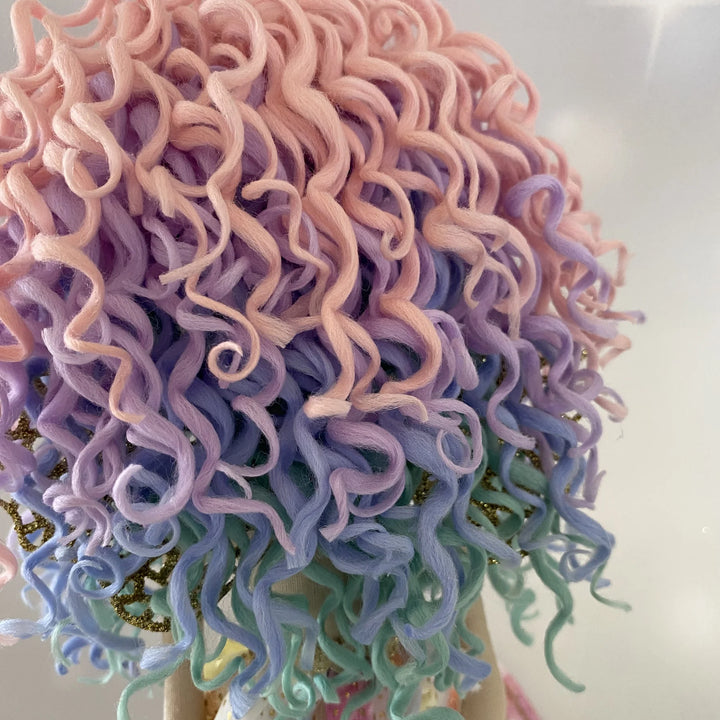 Back view of the Kalani Auralis mermaid doll’s hand-rolled pastel rainbow curls, displaying the full blend of pink, lilac, aqua and sky-blue shades.