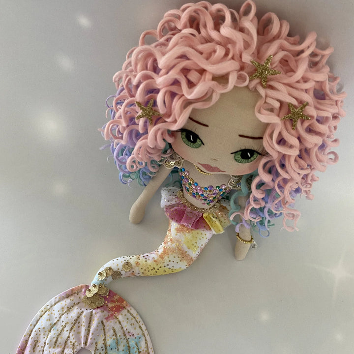 Top-down view of the Kalani Auralis rainbow mermaid doll, showcasing her colourful curls, sparkling bodice and soft pastel tail.